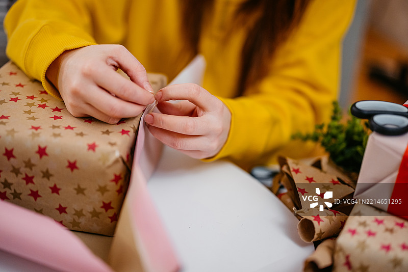 年轻女性在客厅里包裹圣诞礼物，庆祝圣诞假期图片素材