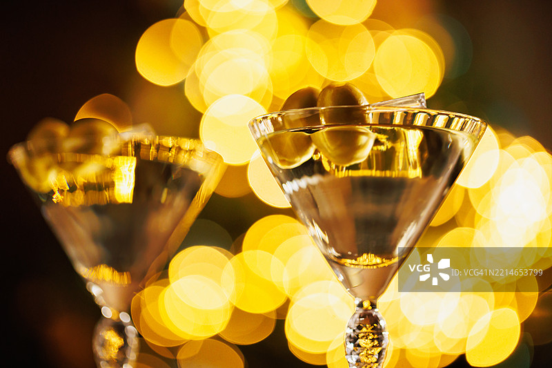 特写的马提尼酒与橄榄和温暖的节日灯光图片素材