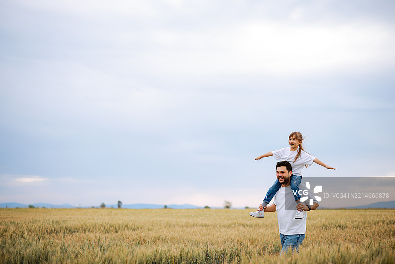 一位父亲在麦田里肩上扛着女儿图片素材