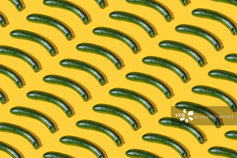 黄色背景上的绿色西葫芦图案。图片素材