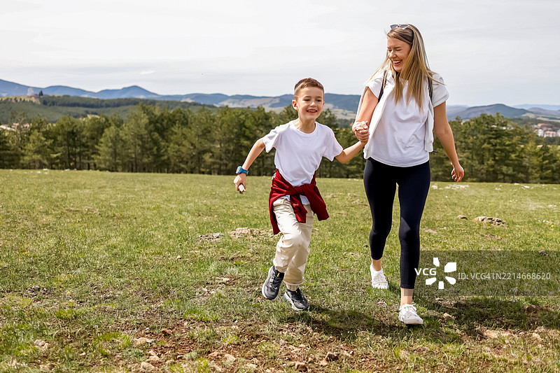 母亲和儿子在风景如画的草地上享受户外乐趣图片素材