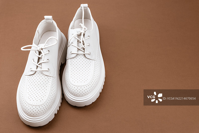 棕色背景上的鞋子。新鞋。图片素材