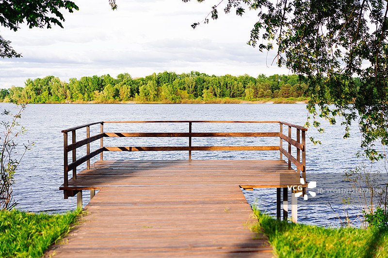 从木栈道俯瞰宁静湖泊的美丽景色，周围绿意盎然图片素材