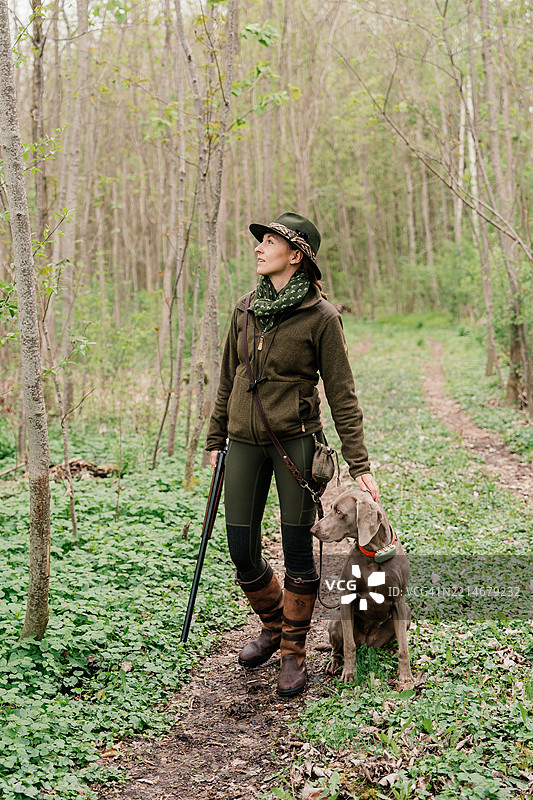 森林中准备去狩猎的女猎人和一只魏玛猎犬图片素材