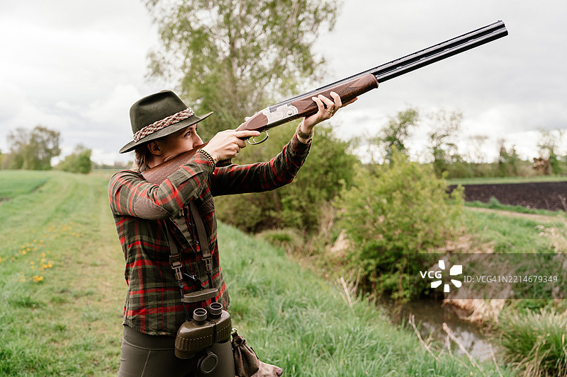女猎人举枪指向天空进行狩猎图片素材
