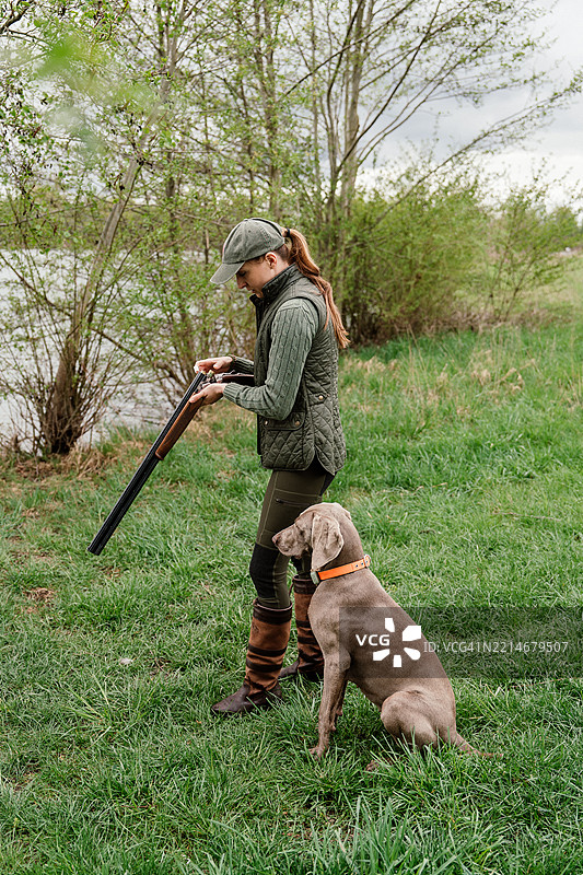 女猎人和她的狗在湖边准备猎枪打鸭子图片素材