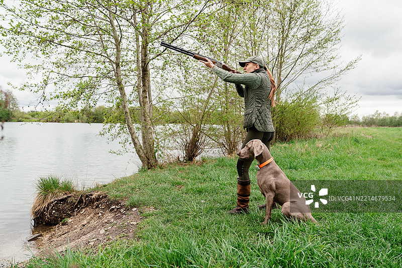 女猎人和她的狗在湖边猎鸭图片素材