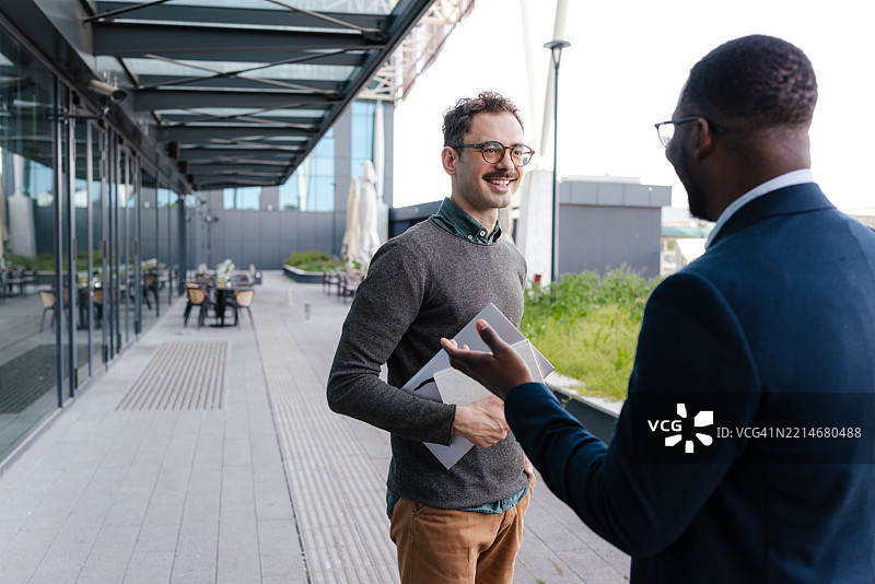 两位专业人士在现代办公大楼外进行友好的交谈图片素材
