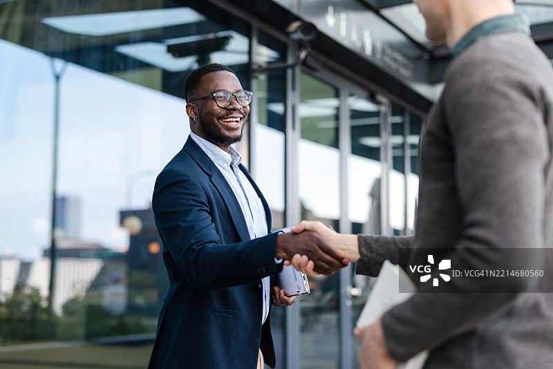 同事们在现代办公大楼外进行专业握手图片素材