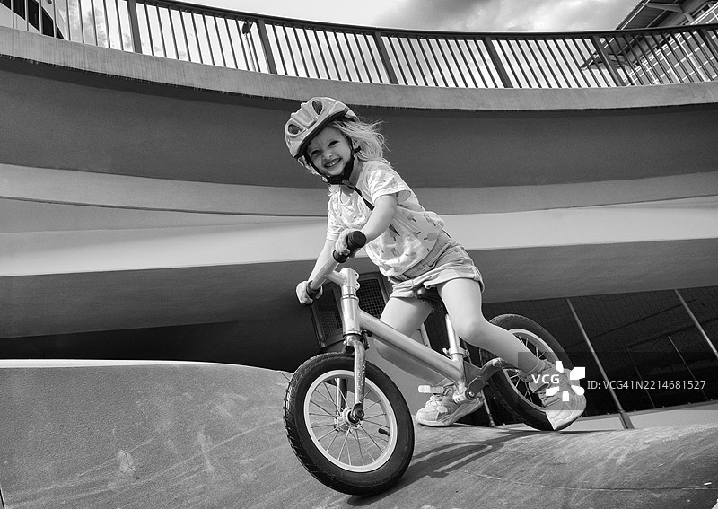 金发女孩，3岁，笑着骑自行车，佩戴安全头盔，地铁，城市，混凝土，黑白色，斯图加特，巴登-符腾堡州，德国，欧洲图片素材