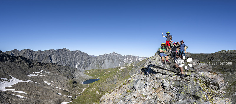 一群登山者在Göseleswand峰顶，山脉景观中有岩石山峰，俯瞰山谷和Bödensee湖以及Panargenkamm，Lasörlinggruppe，霍赫陶恩国家公园，东蒂罗尔，蒂罗尔，奥地利，欧洲图片素材