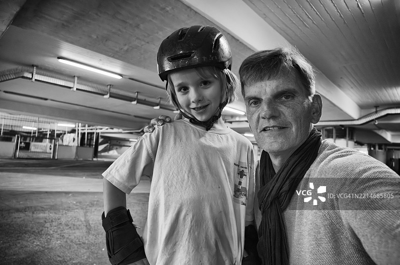 金发男孩，6岁，戴着头盔，穿着保护服，和一位年长男性在地铁里摆姿势自拍，城市环境，混凝土，黑白色调，斯图加特，巴登-符腾堡州，德国，欧洲图片素材