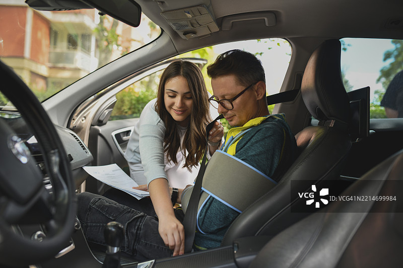 支持的女性在车内为受伤的男性亲属系安全带图片素材