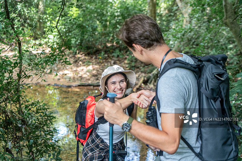 快乐的年轻情侣在林间漫步。图片素材