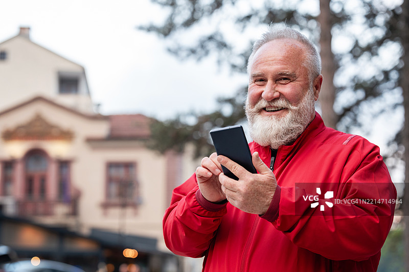 一位留着胡子的老年男子在市中心使用手机图片素材