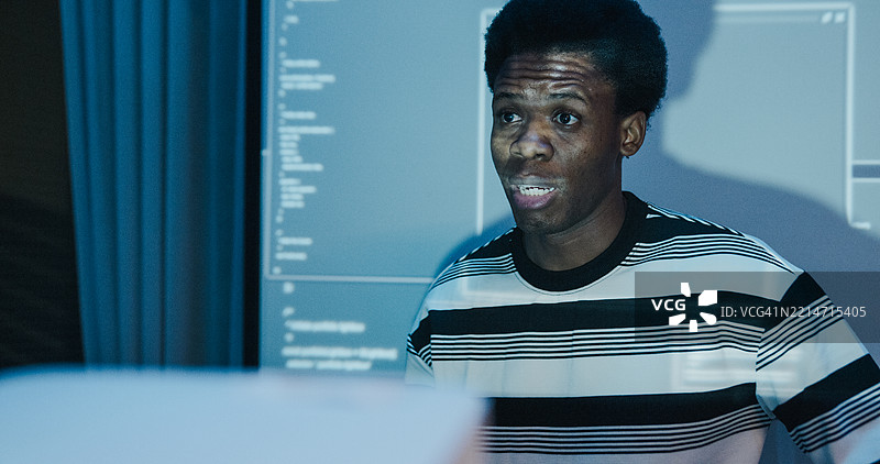 夜间办公室中，来自不同背景的IT专业人士近距离展示编码和网络安全。人工智能与编程。图片素材