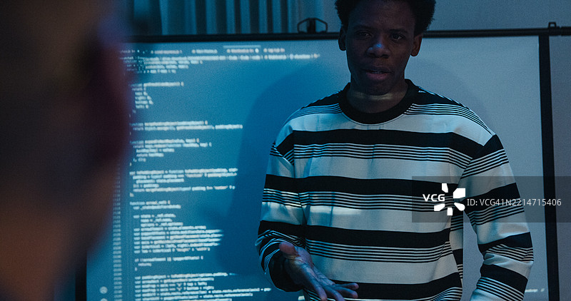 多元化的IT专业团队在夜间办公室展示编码和网络安全。人工智能与编程图片素材