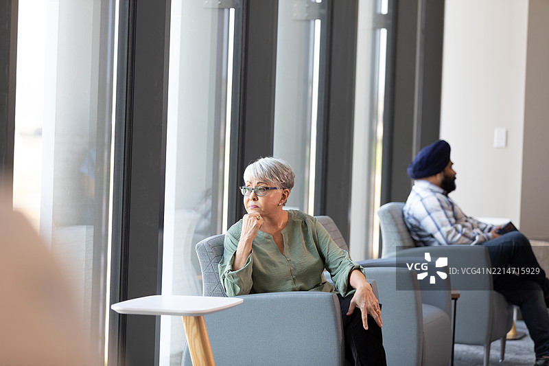 沉思的成熟的女性坐在候诊室里图片素材