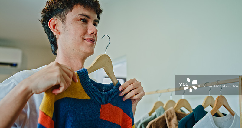 年轻男子自信地选择服装，站在家中卧室的镜子前。健康的早晨生活方式。图片素材