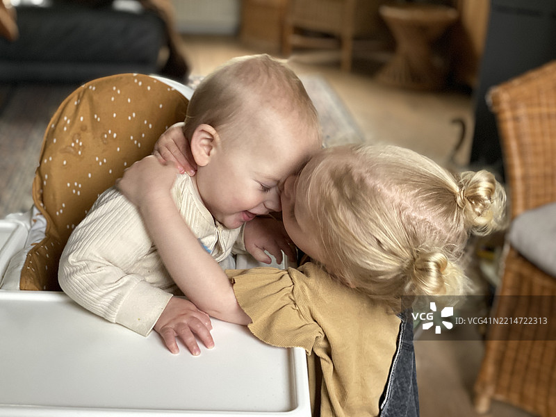 小女孩靠近她的婴儿弟弟图片素材