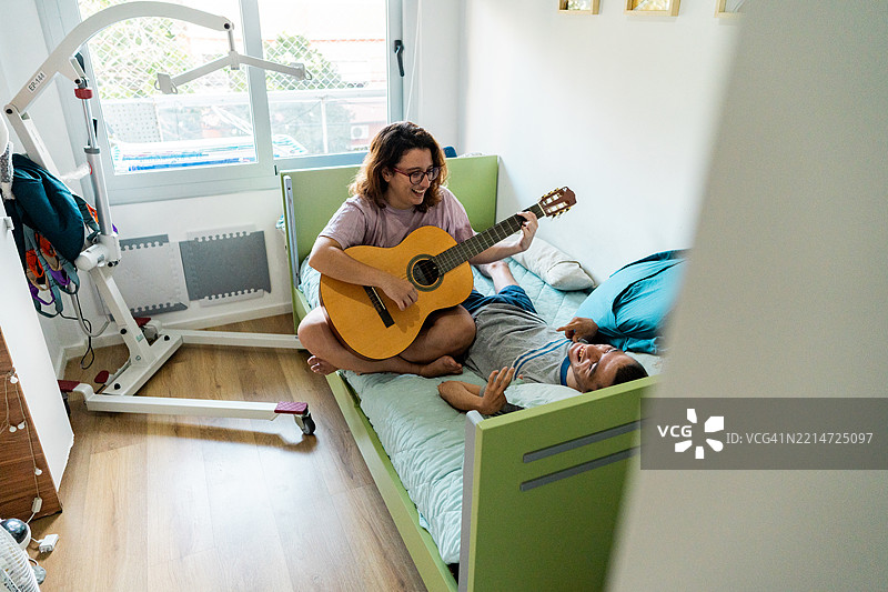 年轻女子在家中为有心理疾病的哥哥弹吉他图片素材