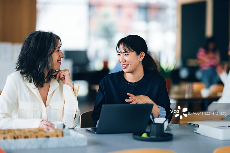 两位职业女性在休闲的办公室环境中友好地交谈图片素材