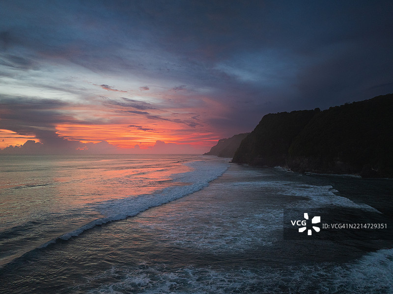 航拍图像展示印度洋上空的日落以及印尼巴厘岛乌鲁瓦图的海岸悬崖图片素材