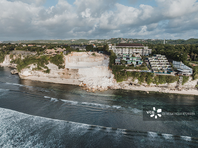 航拍图像显示印度洋边缘的海滩被滑坡覆盖，滑坡是由于在巴厘岛巴东区乌鲁瓦图海岸挖掘石灰岩悬崖以建造别墅所致。图片素材