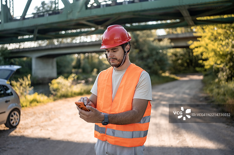 在桥附近的户外，建筑工人使用智能手机图片素材