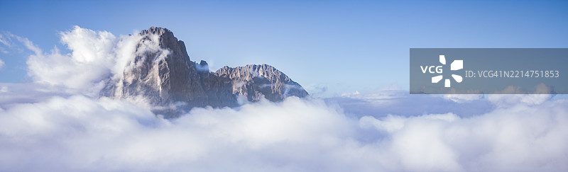 山峰从云层中显现，映衬着晴朗的蓝天图片素材