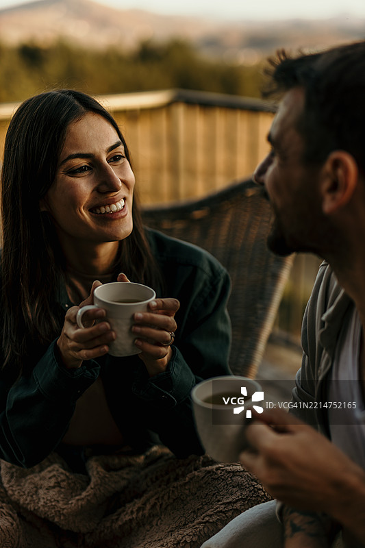 年轻情侣在阳台上享受日落时光，悠闲地喝茶图片素材