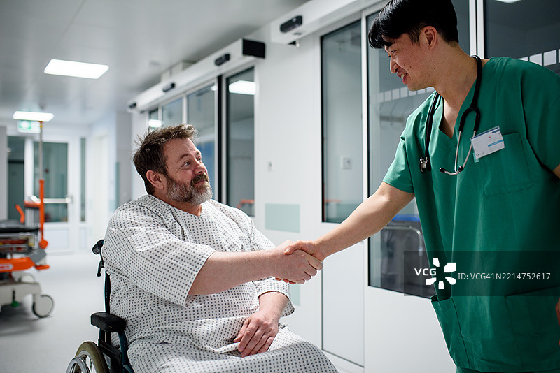 医生与坐在轮椅上的病人握手。图片素材