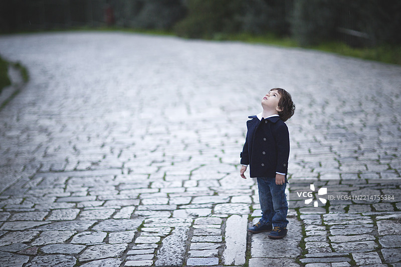 孩子在白天的鹅卵石小路上仰望天空图片素材