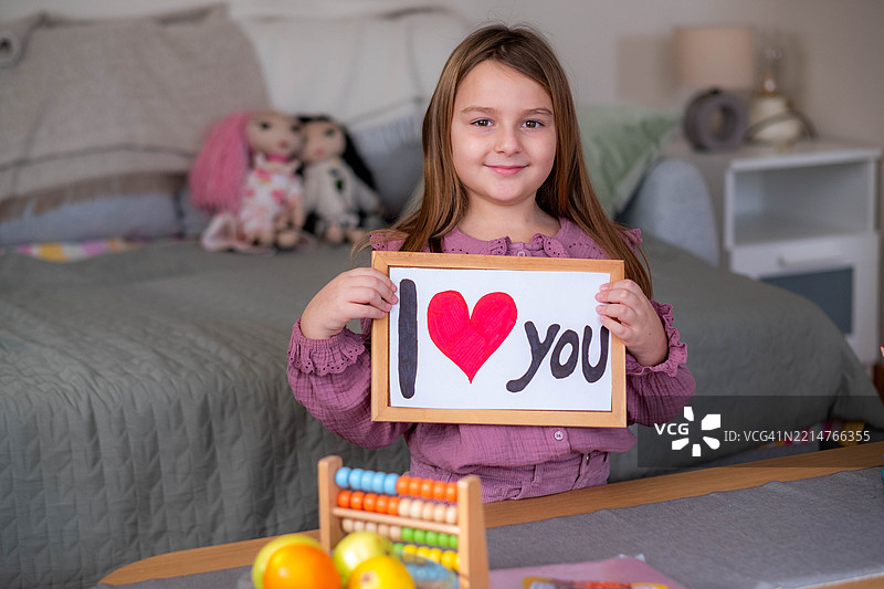 一个女孩手持写有“我爱你”的标志的肖像图片素材