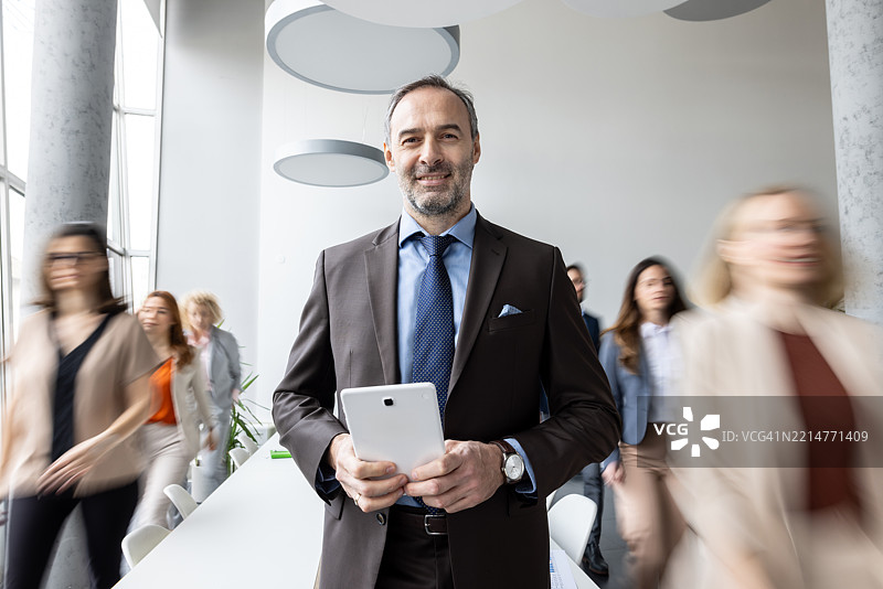 在繁忙办公室背景下的商务专业人士与平板电脑图片素材