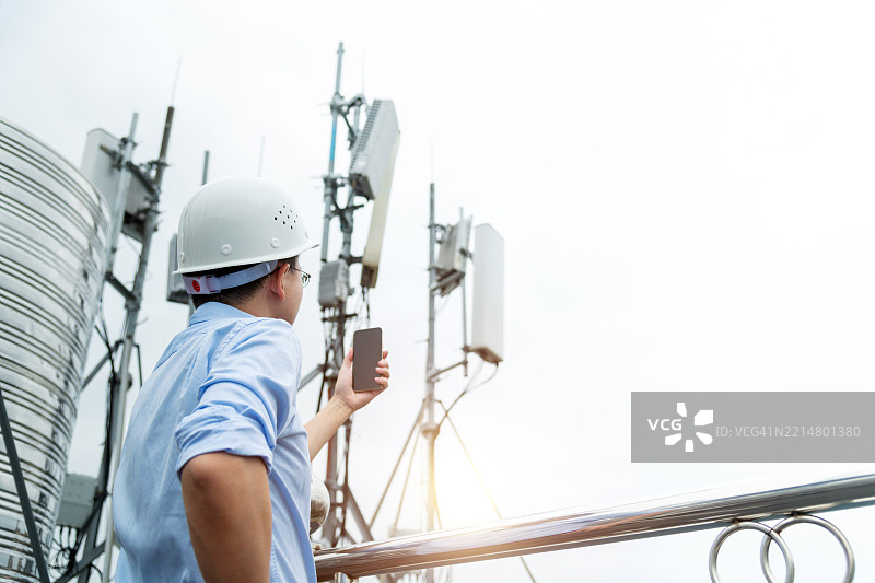 工程师在5G通信塔附近使用手机图片素材