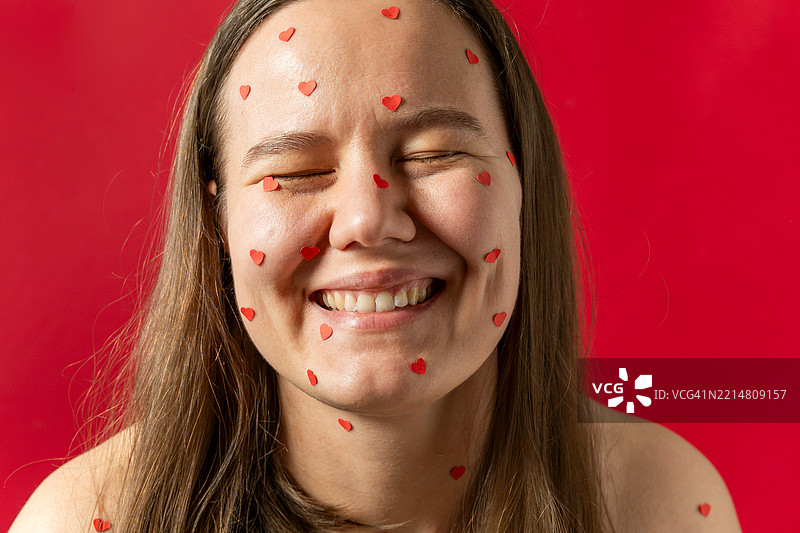 脸上贴着心形贴纸的笑女人图片素材