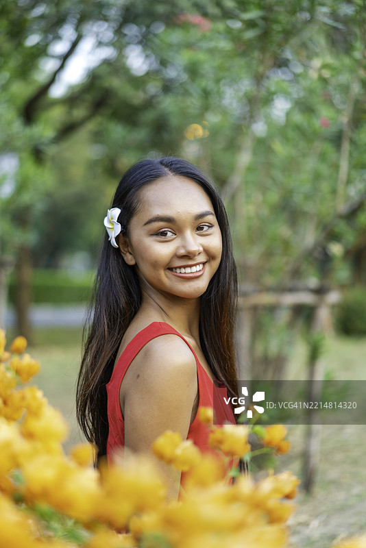 年轻亚洲女性在盛开的花园中享受放松时刻，沉浸在大自然中图片素材