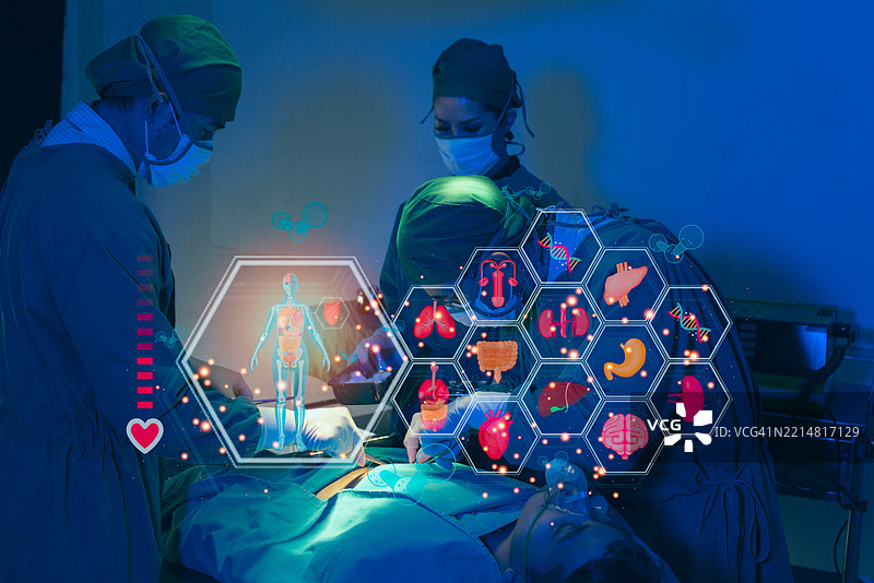 一组外科医生正在为一名患者进行手术，墙上挂着心电监护仪。图片素材