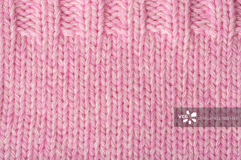 柔和粉色的针织面料特写，展示了复杂的纹理和图案，适合纺织设计、时尚或手工艺项目，具有舒适的美感。图片素材