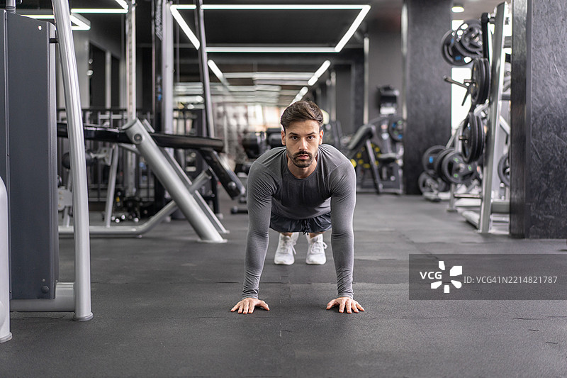 专注的男子在健身房地板上做平板支撑练习图片素材