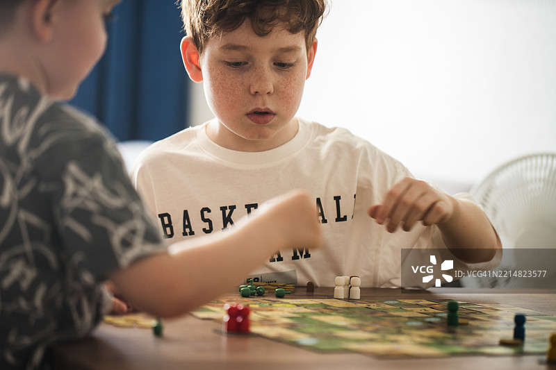 年轻男孩们在室内一起玩策略棋盘游戏图片素材