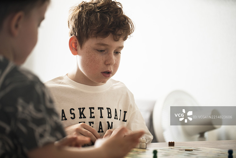 两个兄弟在家里一起享受玩桌游的乐趣图片素材