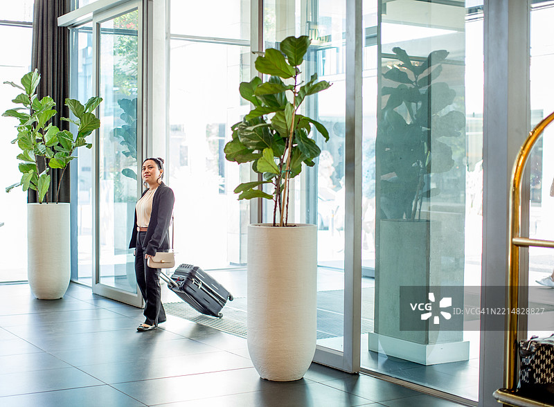 女商人带着旅行行李走进酒店大堂图片素材
