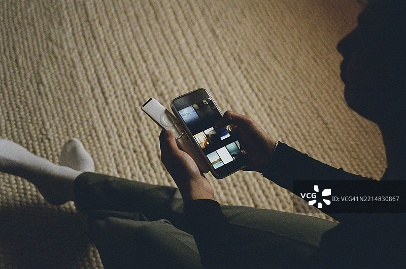 男孩坐在家中，俯视角度使用智能手机。图片素材