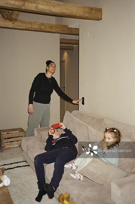 母亲在家中沙发上为孩子们调节温度图片素材