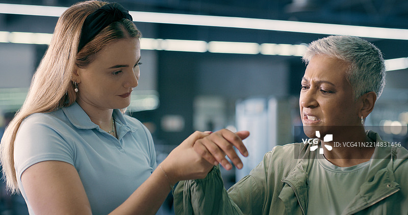 健身房内的私人教练与手腕疼痛的成熟的女性进行锻炼，专注于提高灵活性。运动俱乐部，健身与教练，帮助有手部受伤、事故和炎症的老年人。图片素材