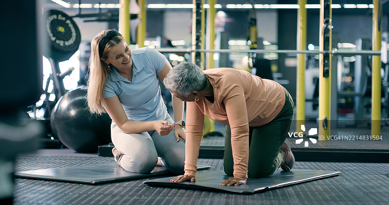 健身房内的私人教练、瑜伽垫和成熟的女性进行锻炼、训练以提高灵活性。运动俱乐部、健身和教练与个人一起促进健康、活跃和心肺健康的运动。图片素材