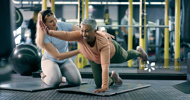 健身房中伸展和快乐的女性私人教练，进行运动、锻炼和灵活性训练。运动俱乐部、健身和教练与成熟人士一起促进健康、活跃和运动。图片素材