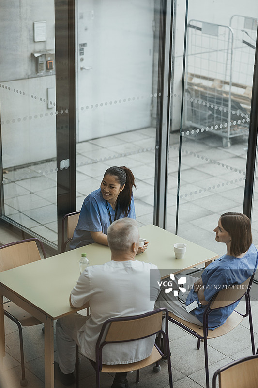高角度视图的男女医生坐在自助餐厅的桌子旁图片素材